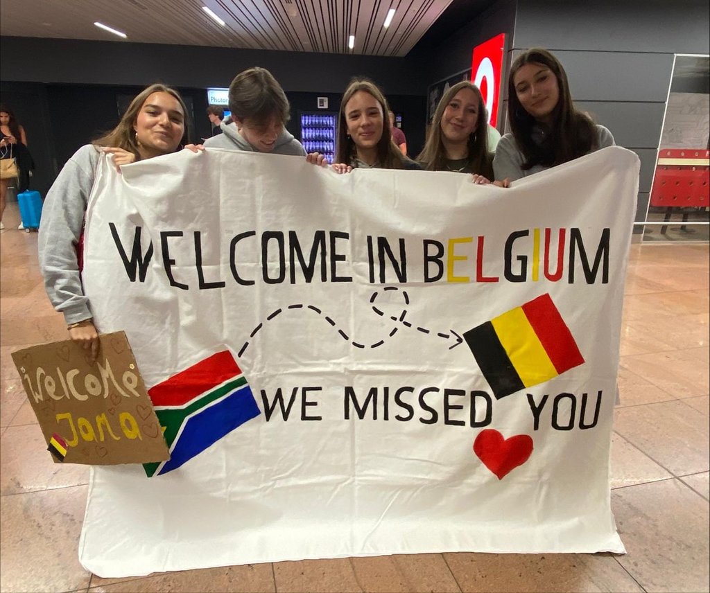 Leerlingen in de luchthaven tonen spandoek 'Welcome in Belgium'